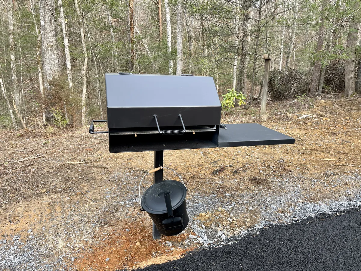 This exterior shot presents a grill accompanied by a side table, surrounded by greenery. The scene suggests casual barbecues, picnics, and relaxed outdoor meals with loved ones, with ample space for everyone.