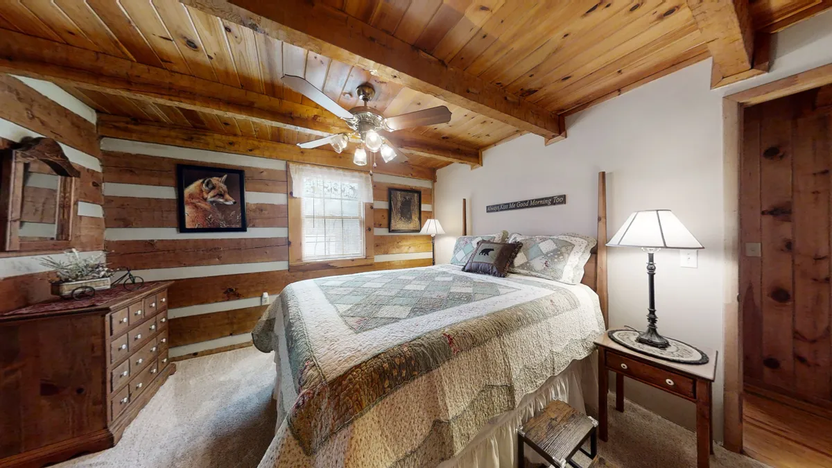 A spacious, sunlit bedroom with a quilted bed, wooden dresser, lamps for reading, and framed artwork on the walls. The soft light and comfortable furnishings create a restful, homey environment ideal for relaxation after a day of adventure.
