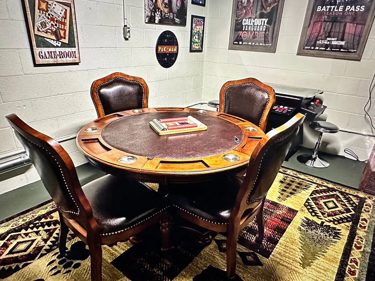 A poker table surrounded by leather chairs, with gaming posters and a rug creating a playful, inviting atmosphere. The setup is perfect for hosting poker nights, playing board games, or sharing celebrations with friends and family.